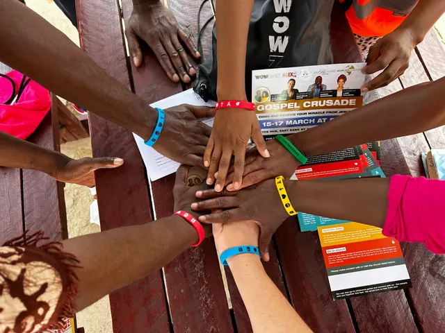 Ministry team placing hands together around outreach resources